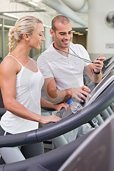 Male trainer timing his client on treadmill at gym