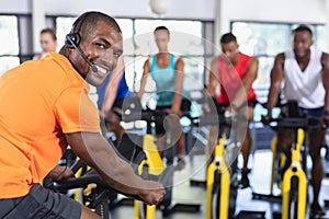 Male trainer training people to work out on exercise bike