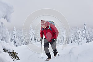 Male traveler climbs a mountain during a snowfall