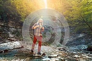 Male traveler cross the mountain river for a wade