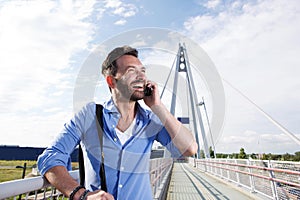 Male traveler standing on bridge and talking on cell phone