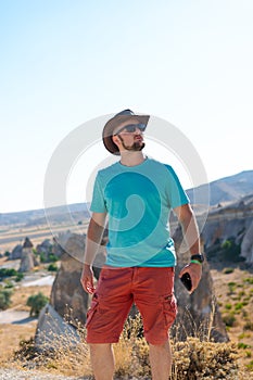 Male traveler in sunglasses, tourist Fairy chimneys park background rock formations Travel and vacation, Vertical photo. tour to
