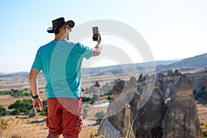 Male traveler takes selfie, photo on smartphone, tourist Fairy chimneys park background rock formations Travel and vacation,