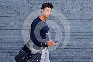 Male traveler walking with mobile phone and bag