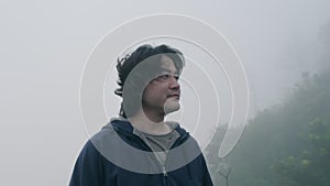 Male traveller enjoying the view at the top of mountain with thick fog in the early morning in the background. Lifestyle on vacati