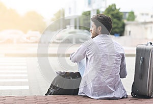 Male Traveller Sitting On Ground Near Airport Next To His Luggage