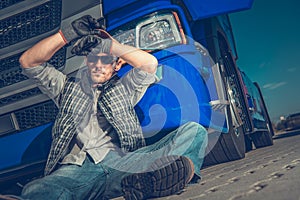 Male Trucker Sitting On Ground At Rest Stop Area