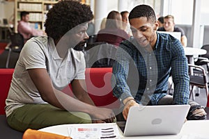 Male University Student Working In Library With Tutor