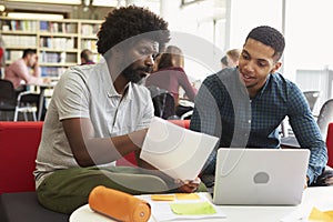 Male University Student Working In Library With Tutor