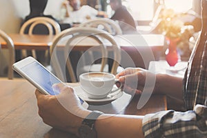 Male using a smart phone with coffee cup on wooden table