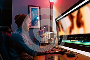 Male Video Editor sitting at his Computer using phone