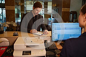 Male visitor filling registration form at reception desk