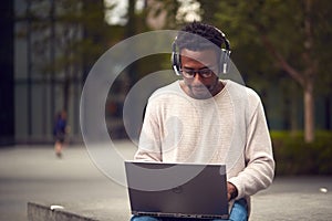 Male Vlogger Or Social Influencer Travelling Through City For Social Media Using Laptop Outdoors