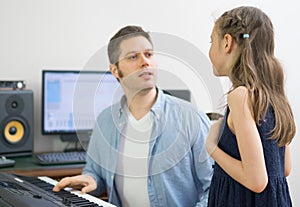 Male vocal coach teaching little girl how to sing.