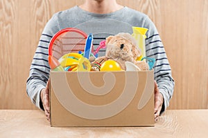 Male volunteer holding donation box with old toys.