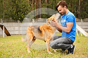 Male volunteer with homeless dog at animal shelter