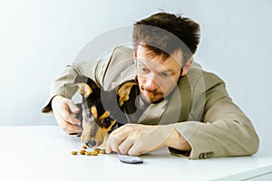 male volunteer playing with a dog from a kennel. they eat dog food together.