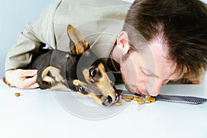 male volunteer playing with a dog from a kennel. they eat dog food together.
