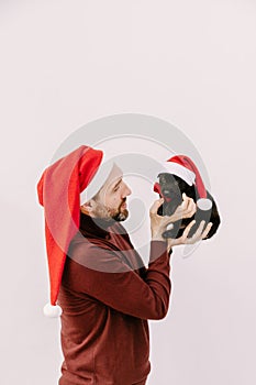 male volunteer in a Santa hat is holding a puppy with a Santa hat.