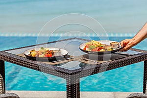 Male waiter hand serving lunch in restaurant at hotel, summer vacations concept