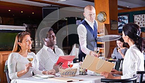 male waiter serving order to friends in restaurante