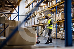 Male warehouse worker pulling a pallet truck.