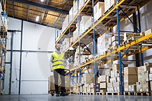 Male warehouse worker pulling a pallet truck.