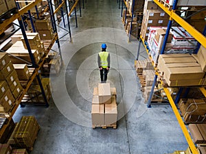 Male warehouse worker pulling a pallet truck.