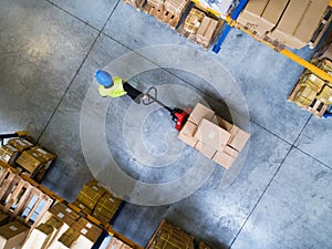 Male warehouse worker pulling a pallet truck.