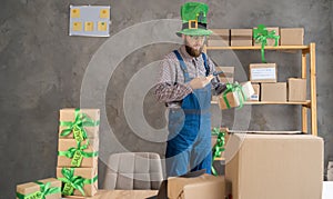male warehouse worker seller in leprechaun hat, small stock business owner holding smartphone, using mobile app scanning