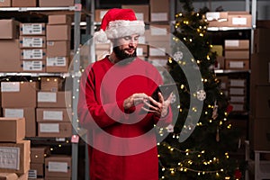 Male warehouse worker working at christmas time using digital tablet to inventory warehouse. Christmas delivery