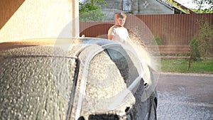 Male washes car. Wash with high pressure water jet, spray is scattered to sides