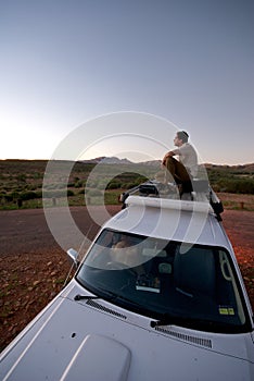 Male Watching Sunset from roof of car