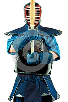 Male wearing a kendo armor with helmet and gloves holding a bamboo sword.