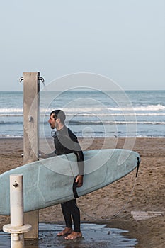 Male wearing a neoprene suit holding a surf board