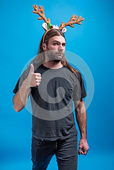 Male wearing raindeer hair band with straight face displaying thumbs up sign