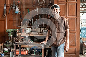 Male welder smiles at the camera holding a metal rack