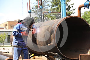 Male welder works. Welding joint of large diameter pipe. High pressure pipe welding for a gas station