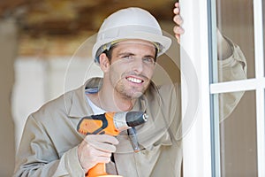 Male window fitter holding cordless drill