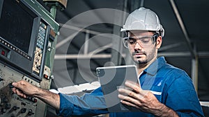 Male worker in blue jumpsuit and white hardhat operating the machine.