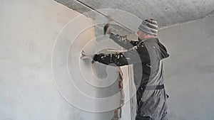 Male worker breaking wall in apartment under renovation.
