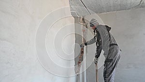 Male worker breaking wall in apartment under renovation.