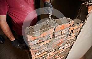 Male worker building brick wall at constructing site.