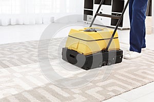 Male worker with carpet cleaner indoors