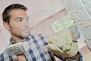 male worker chiselling off plaster