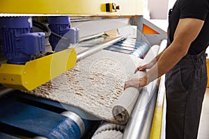 Male worker cleaning carpet on automatic washing machine equipment and dryer in the Laundry room. professional washing