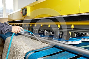 Male worker cleaning carpet on automatic washing machine equipment and dryer in the Laundry room. professional washing