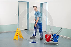 Male Worker With Cleaning Equipments Mopping Floor
