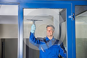 Male Worker Cleaning Glass With Squeegee