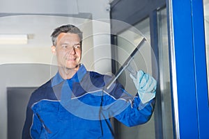 Male Worker Cleaning Glass With Squeegee